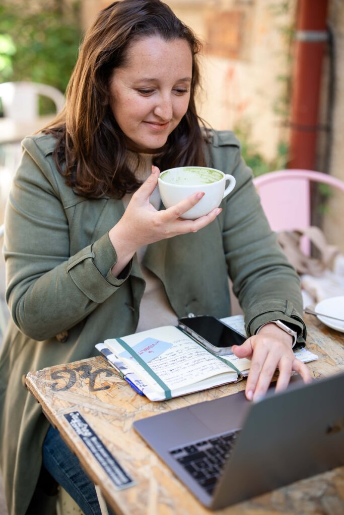 Photo de Laura, créatrice de My Visibility Lab travaillant à la terrasse d'un café