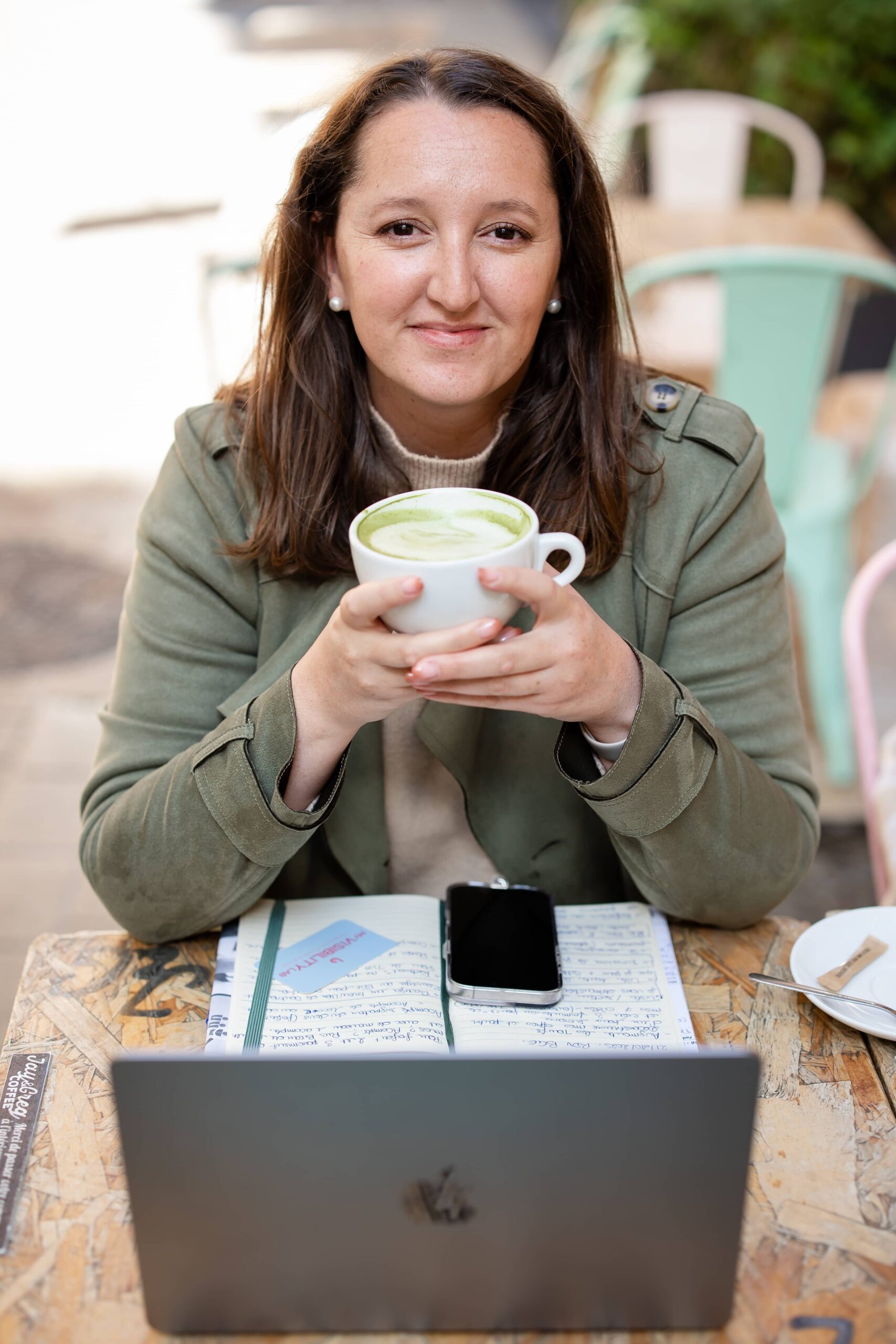 Photo de Laura, créatrice de My Visibility Lab avec son carnet de note, son téléphone et son thé matcha pour illustrer la partie consulting de son activité